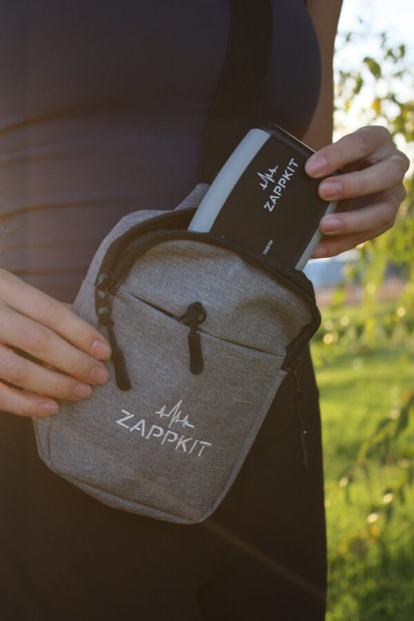 zappkit-z-amplifier-portable-wellness-device-travel-ready Portable Zappkit Z-Amplifier frequency therapy device fitting into a crossbody carrying bag for convenient on-the-go wellness use.